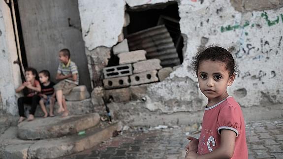 Varios niños palestinos juegan en Gaza delante de casas destruidas durante la ofensiva militar israelí del año pasado.