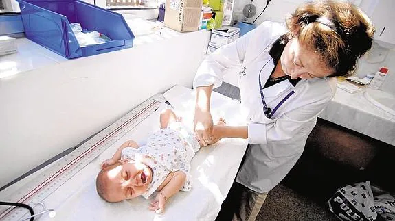 Una pediatra aplica una vacuna a un bebé.