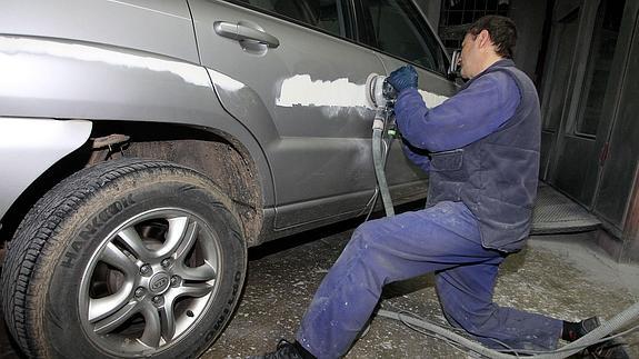 Un mecánico arreglando un coche siniestrado. 