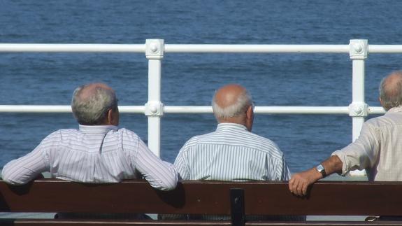 Ancianos toman el aire en el Paseo Marítimo de la playa de San Lorenzo, en Gijón (Asturias).