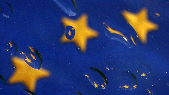 Bandera de la UE vista a través de un cristal mojado por la lluvia.