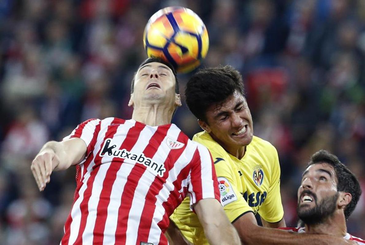 Raúl García cae ante dos futbolistas del Villarreal. 