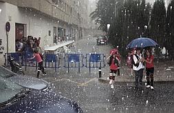 Un grupo de escolares se refugia como puede de la lluvia y el granizo en la tarde de ayer en una calle de Mula. ::                             PACO VERDÚ