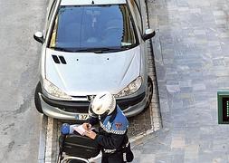 Un agente multando a varios vehículos mal aparcados. Foto: P. Alonso/ AGM