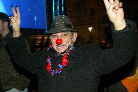 ALEGRÍA. Un hombre con nariz de payaso saluda a la cámara en la plaza de Romea y otro joven recibe el nuevo año pintándoselo en la frente, / EDUARDO BOTELLA/AGM