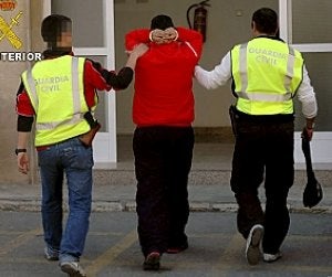 Los agentes custodian a uno de los detenidos en la operación. ::                         G.C.