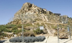 La máquina retroexcavadora trabaja en la ladera cubierta por las redes metálicas que sujetan las rocas. ::                             SONIA M. LARIO / AGM