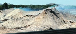 El montón de masa forestal que arde desde el 7 de septiembre, ayer, emanando humo. ::                             I. SÁNCHEZ / AGM