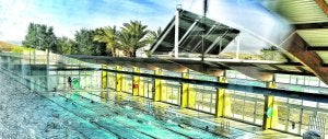 La piscina de Beniel vista desde la terraza, donde están instaladas las placas solares, que se ven reflejadas en el cristal.