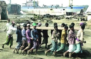 Trabajadores trasladan una plancha de acero de un barco desguazado en Chittagong (Bangladesh).