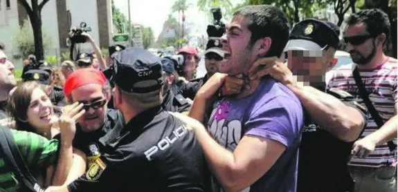 El agente denunciado agarra a un manifestante del cuello durante una protesta. 