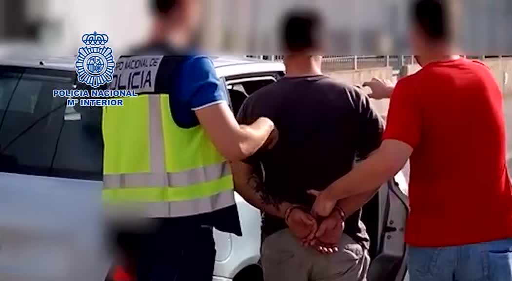 Dos agentes trasladan esposado a uno de los detenidos de la presunta banda