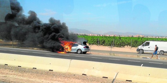 El coche envuelto en llamas en la vía rápida de San Javier, ayer por la tarde.