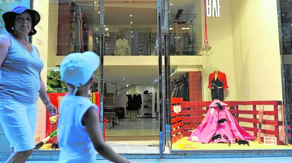 Un niño mira sorprendido el escaparate de la tienda de moda BAF, en la calle Sociedad, que exhibe un capote del torero Manuel Cascales. 