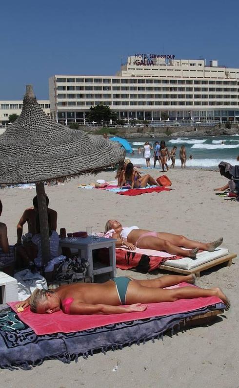 Un grupo de turistas extranjeros toma el sol en el Mar Menor, junto al hotel Galúa. :