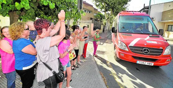 Vecinos de Ermita del Rosario, aplaudiendo en julio la llegada al barrio del Rayo 12. :: NACHO GARCÍA / agm
