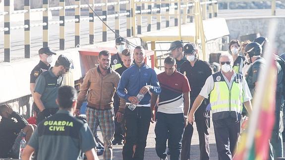 Efectivos de la Guardia Civil y de la Policía Nacional traslada a los ocupantes de la patera al puerto de Cartagena.