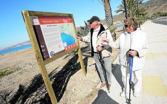 Dos personas consultan un mapa del litoral de La Azohía, durante un paseo por la costa.