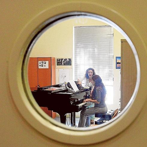 Una profesora da instrucciones a una alumna en el aula de piano.