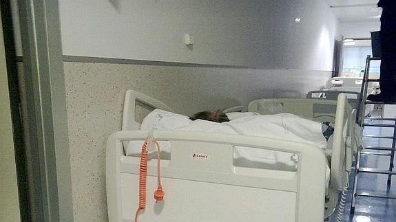 Un paciente, en una de las camas colocadas en un pasillo del Santa Lucía, y a su lado un electricista trabajando, en una imagen tomada ayer.
