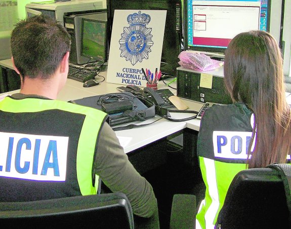 Dos agentes del grupo de Delitos Tecnológicos del Cuerpo Nacional de Policía indagan en una página web. :: cnp