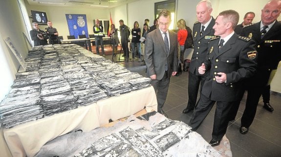 Bascuñana y los mandos policiales miran los paquetes de cocaína embolsada, en una sala de la comisaría. 