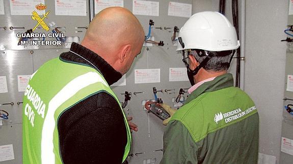 Un guardia civil revisa los contadores con la ayuda de un empleado de Iberdrola. 