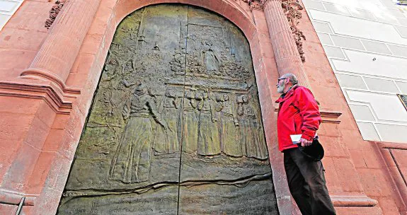 Un cofrade blanco observa las nuevas puertas de bronce de la capilla del Rosario.