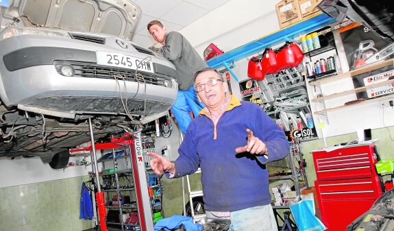 Damián Tari, en lo alto de la escalera, y su padre, Francisco Tari, en su taller de coches de Cuesta Blanca. 