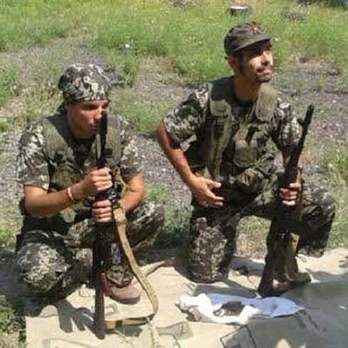 El cartagenero Ángel David (d) sujeta un fusil de asalto mientras recibe indicaciones de un rebelde prorruso.