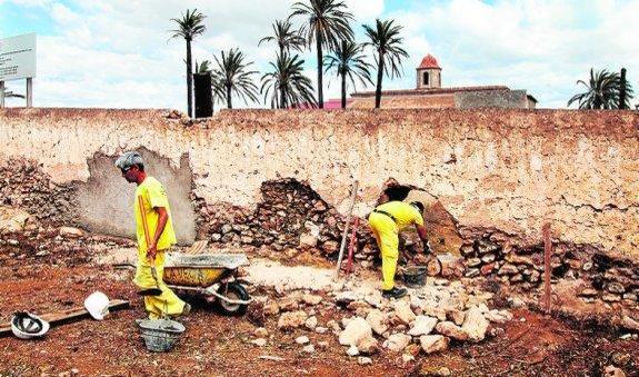 Dos operarios arreglan el muro del monasterio. 