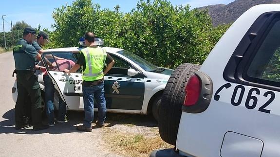 Agentes de la Benemérita conducen al detenido al coche patrulla.