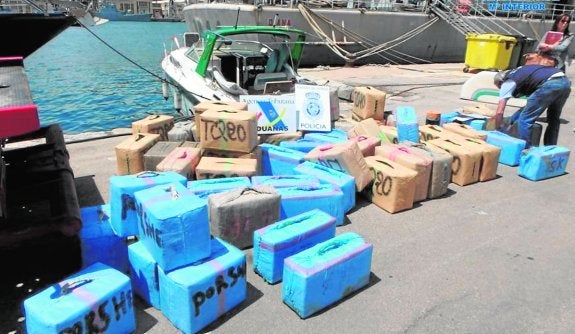 Los 65 fardos de hachís, frente al yate que los transportaba, ayer, en el Puerto de Cartagena. 