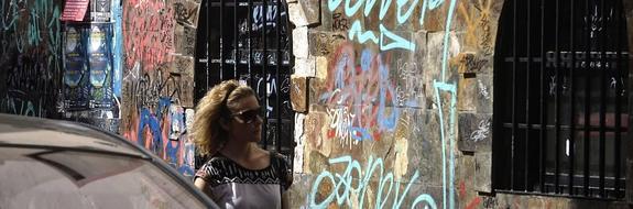 Una joven pasa ante las numerosas pintadas que recubren la fachada de un edificio en la calle Jacobo de las Leyes. 