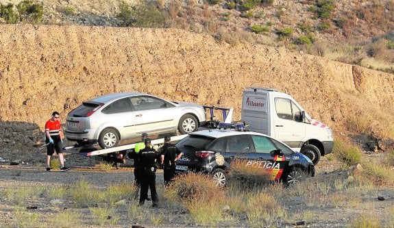 Agentes de la Policía Nacional observan cómo una grúa traslada el vehículo del militar fallecido.