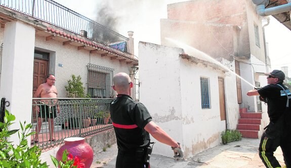 Un vecino observa el trabajo de los bomberos para atajar el fuego, cercano a su casa. 