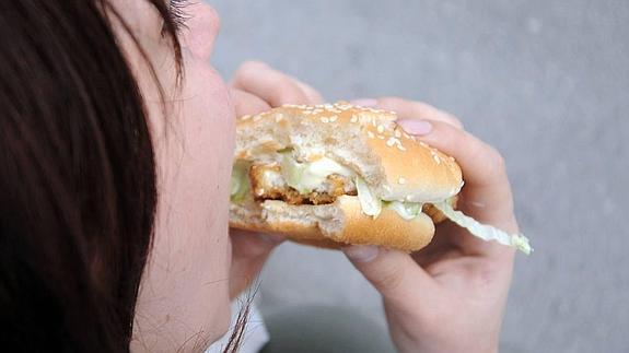 Mujer comiendo hamburguesa. 