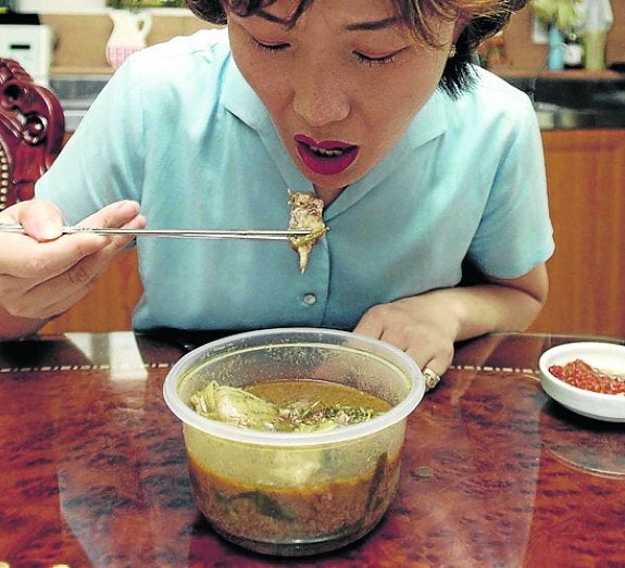 Una mujer come sopa de carne de perro. 