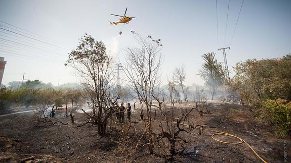 El helicóptero de Emergencias y efectivos de bomberos tratan de sofocar el incendio. 