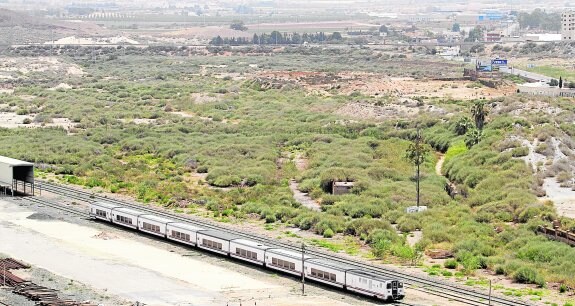 Un tren circula por el pasillo ferroviario junto a la extensión en la que estaba previsto el nuevo ensanche de El Hondón. 