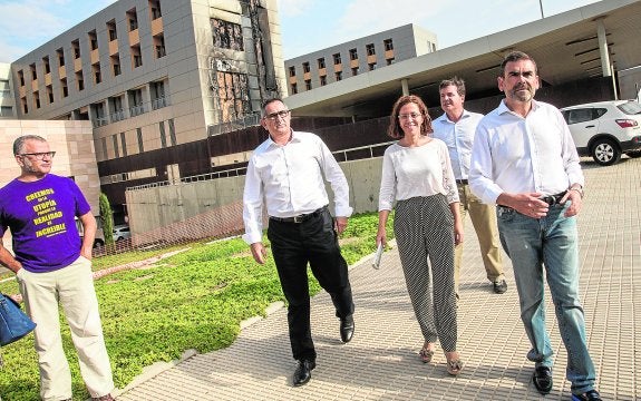 Un miembro de la plataforma Salvemos el Rosell mira a Pedro López, Ana Belén Castejón, Antonio Jesús García y José López, frente a la fachada del Santa Lucía incendiada.
