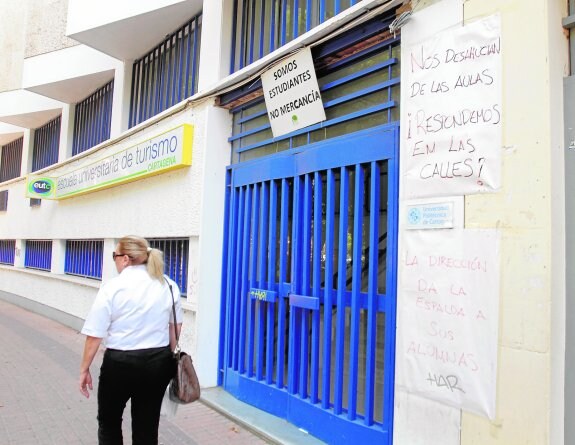 Una mujer pasa por la sede de la Escuela de Turismo de Cartagena, en la Plaza de España, cerrada a finales de junio.