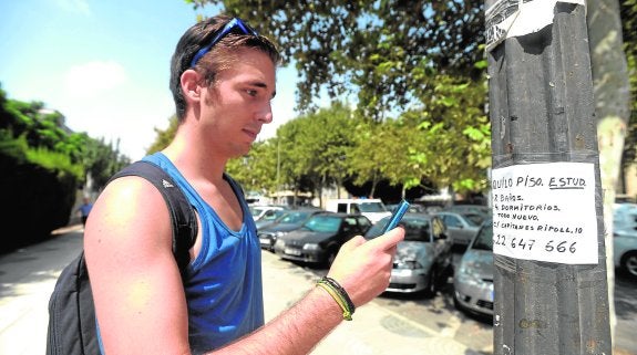 Un universitario apunta en su teléfono móvil el número de una vivienda que se alquila. 
