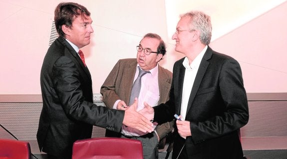 El presidente del Consejo Social estrecha la mano del exgerente en presencia del rector. 