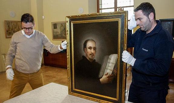 Dos técnicos del Museo de Bellas Artes de Murcia sostienen el cuadro 'San Ignacio de Loyola', de Francisco de Goya, este miércoles en San Esteban.