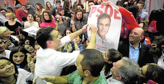Pedro Sánchez firma uno de los carteles con su imagen al entrar ayer tarde en el pabellón Príncipe de Asturias de Murcia. 