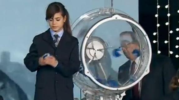 Una de las niñas de San Ildefonso extrae una bola del bombo. 