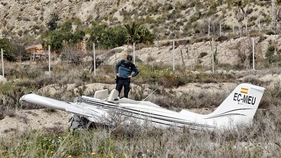 Un agente de la Guardia Civil inspecciona el ultraligero accidentado. 