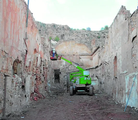 A la izquierda, uno de los técnicos que han participado en el estudio arqueológico encargado por la Concejalía de Obras examina la parte alta de los muros interiores de la ermita de San Lázaro. Arriba, detalle de pinturas murales que se han hallado en una de las hornacinas del monumento.