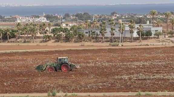 Un tractor, junto a la oficina de ventas del residencial Novo Carthago, con el Mar Menor al fondo, en una imagen de archivo.